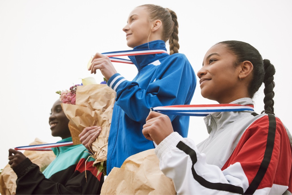Three young female athletes celebrating their achievements together
